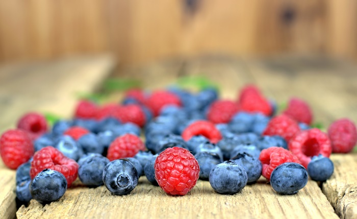 Raspberries and blueberries on a wooden surface