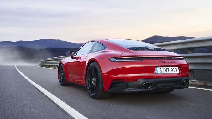 Red Porsche 911 Carrera GTS driving on a road