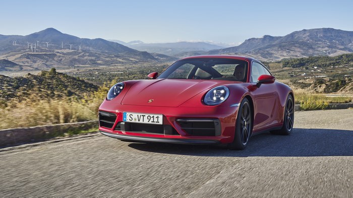 Red Porsche 911 Carrera GTS driving on a road