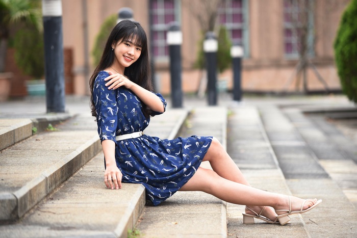 Young Asian woman in a blue dress sitting on steps