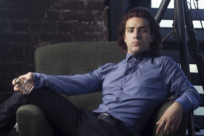 Man holding perfume bottle in armchair