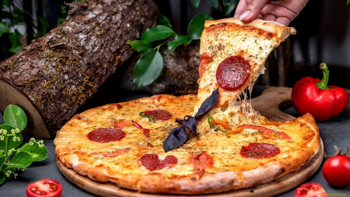 Pepperoni pizza with cheese and basil on a wooden board