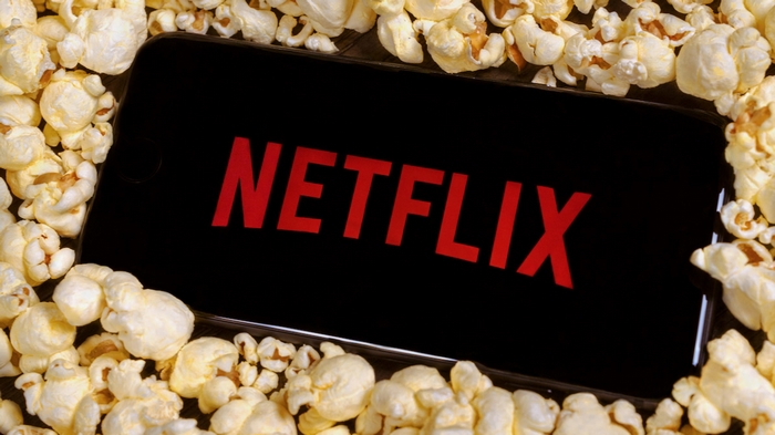 Netflix logo on smartphone surrounded by popcorn