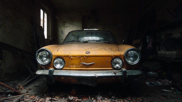 Abandoned yellow FIAT car in a dark garage
