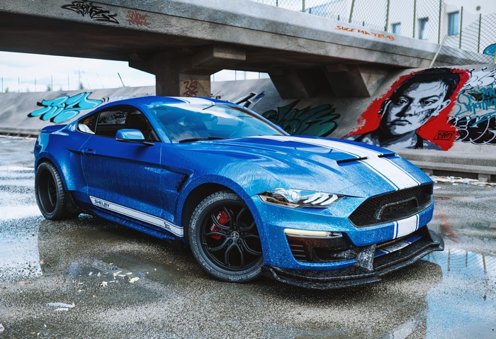 Blue Shelby Mustang with white stripes on wet asphalt