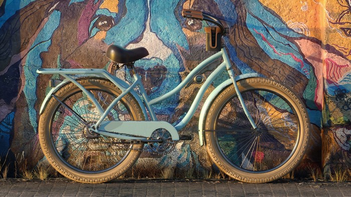 Light blue bicycle parked against a colorful graffiti wall