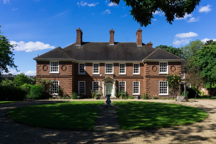 Brick mansion with manicured lawn and trees
