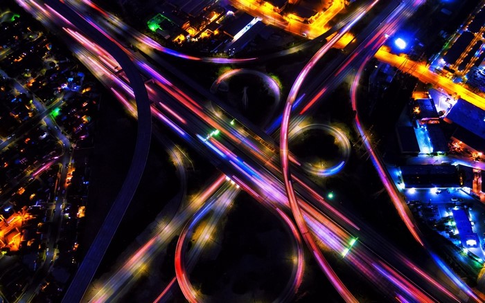 Aerial view of a highway interchange at night with light trails