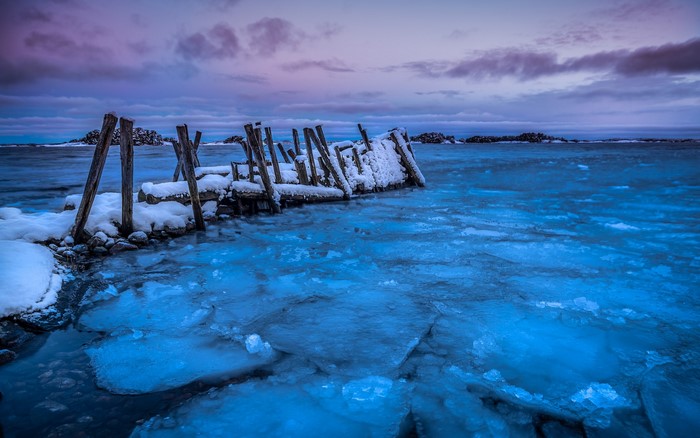 Frozen pier with ice and snow at dusk