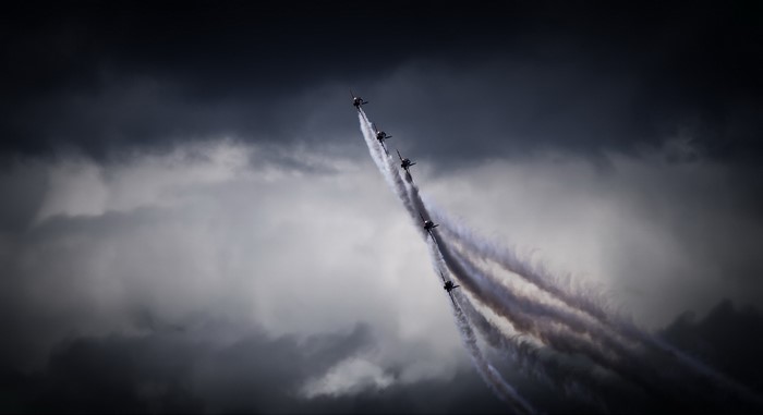 Red Arrows formation flying through dark clouds