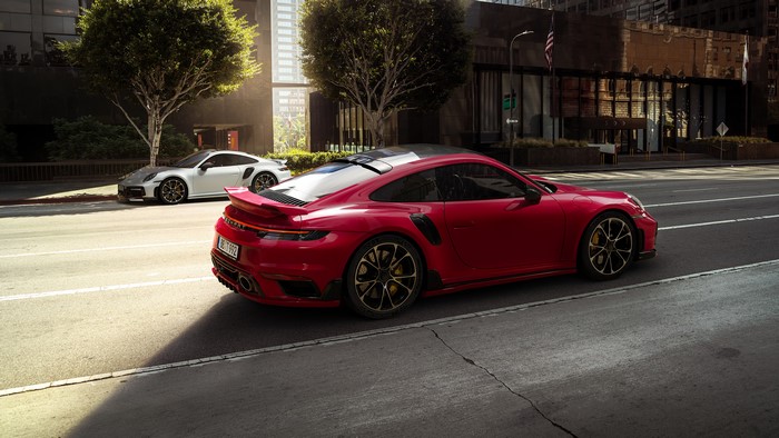 Red and white Porsche 911 sports cars on urban street
