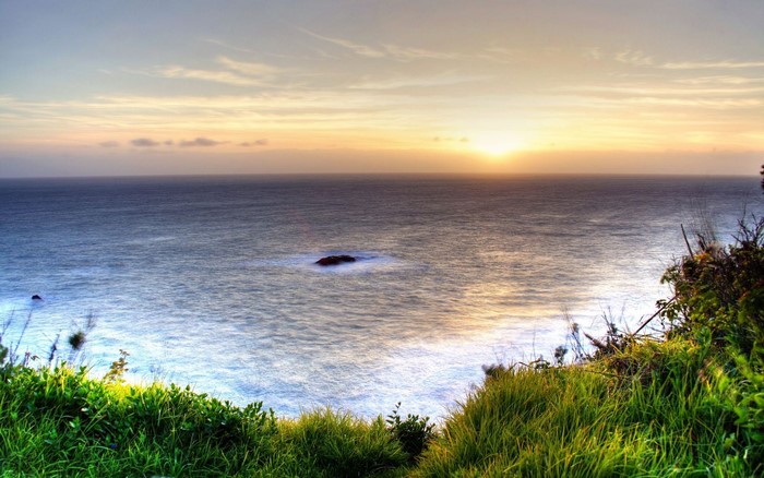 Ocean sunset with grassy cliffside