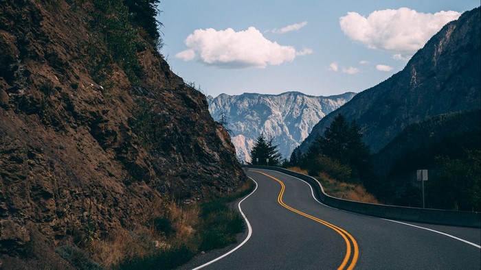 Winding mountain road with rocky cliffs and distant peaks
