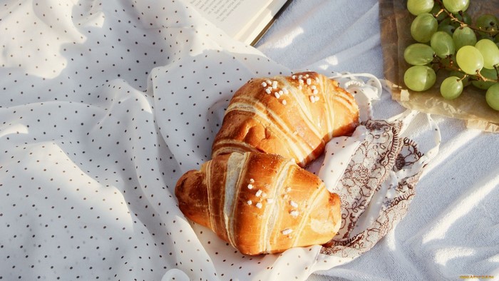 Croissants and grapes on a picnic blanket