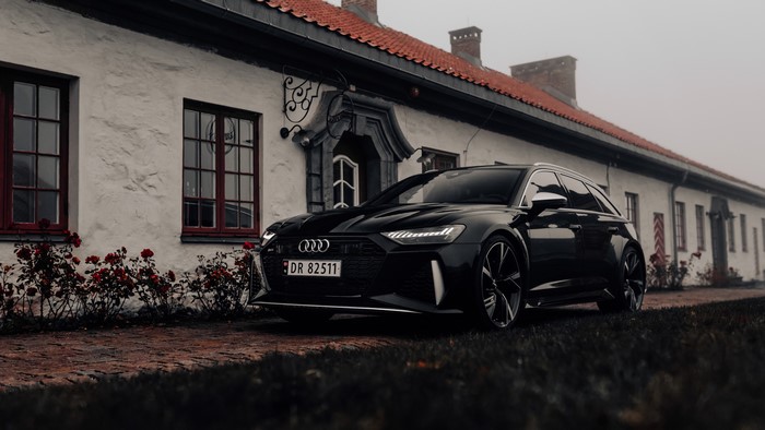 Black Audi RS6 Avant parked in front of a white building