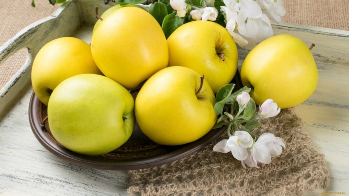 Yellow and green apples on a tray with flowers