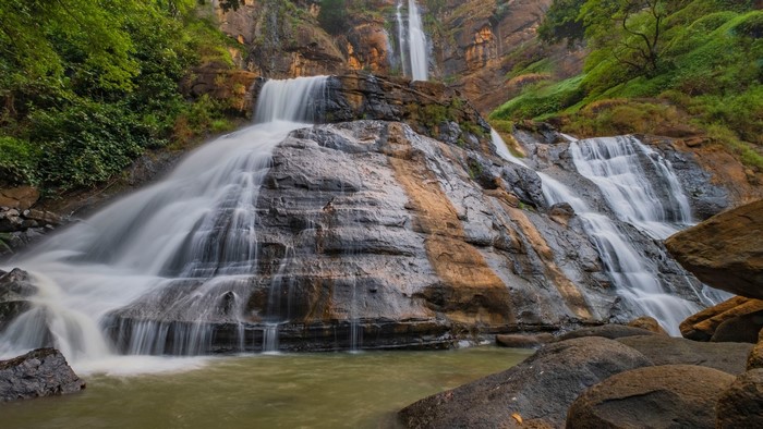 Waterfall cascading over rocky cliffs with lush greenery