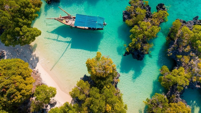 Aerial view of a boat in turquoise water near a tropical island