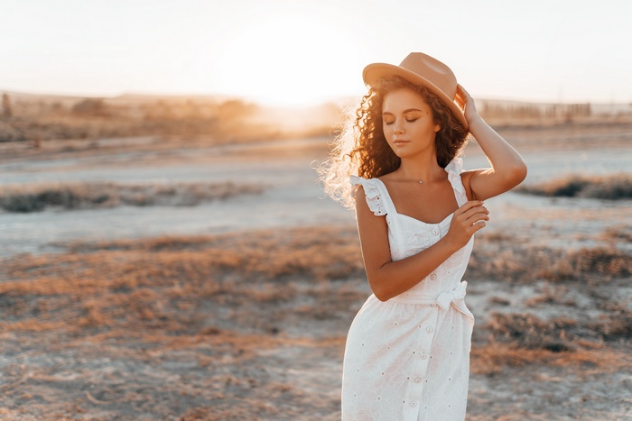 Woman in white dress and hat at sunset