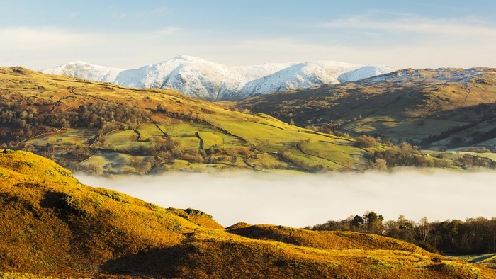 Snow-capped mountains over a misty valley and rolling hills