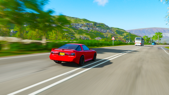 Red Toyota Supra driving on a road in Forza Horizon 4