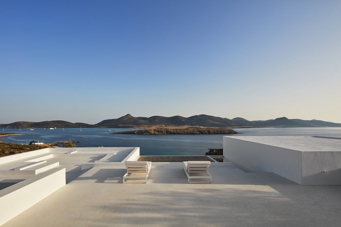 White terrace with lounge chairs overlooking the sea and mountains