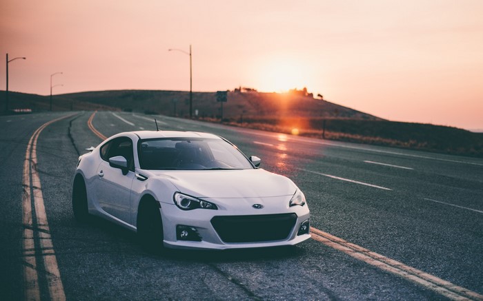 White Subaru BRZ on a winding road at sunset