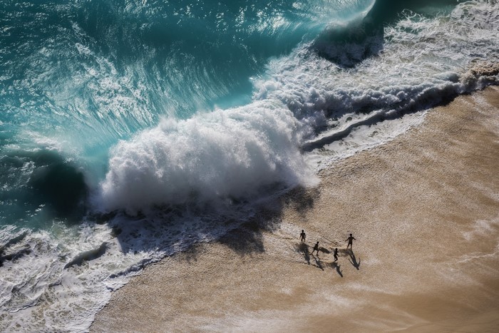 Aerial view of people on a sandy beach with crashing waves