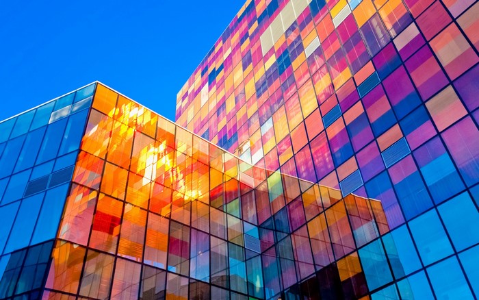 Colorful glass building facade against a clear blue sky