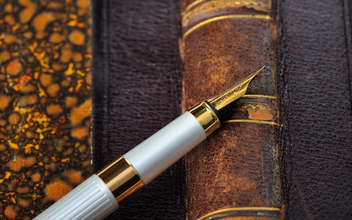 Fountain pen resting on vintage leather-bound books