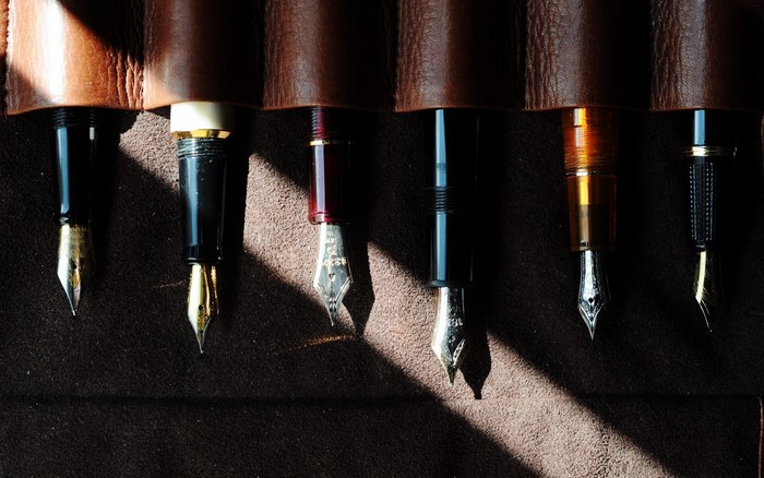 Collection of vintage fountain pens in a leather roll