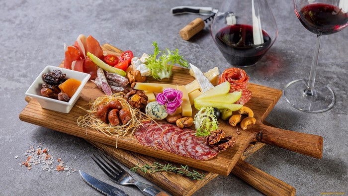 Charcuterie board with wine, cheese, meats, nuts, and dried fruit