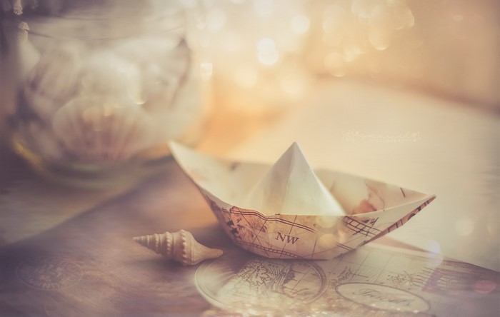 Paper boat and seashell on a map