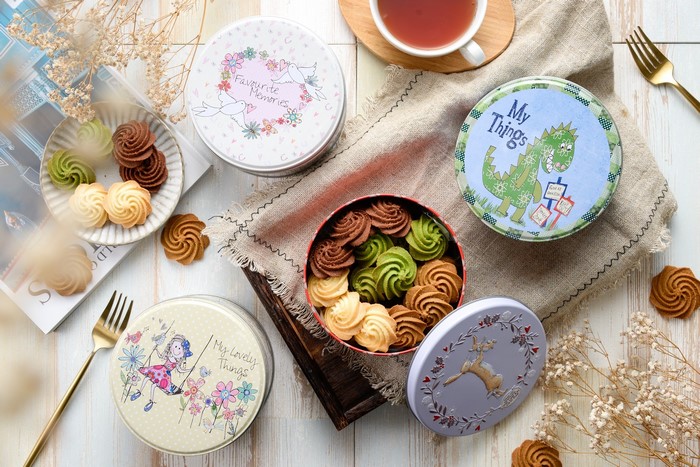 Assorted cookies in decorative tins with tea and forks