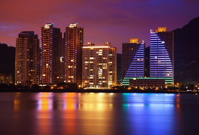 Cityscape with illuminated buildings at night reflected in water