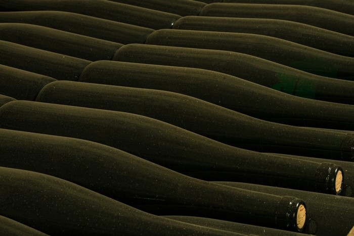 Dusty wine bottles stacked in cellar