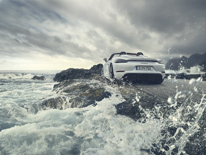 White Porsche 718 Spyder on rocky seashore with waves
