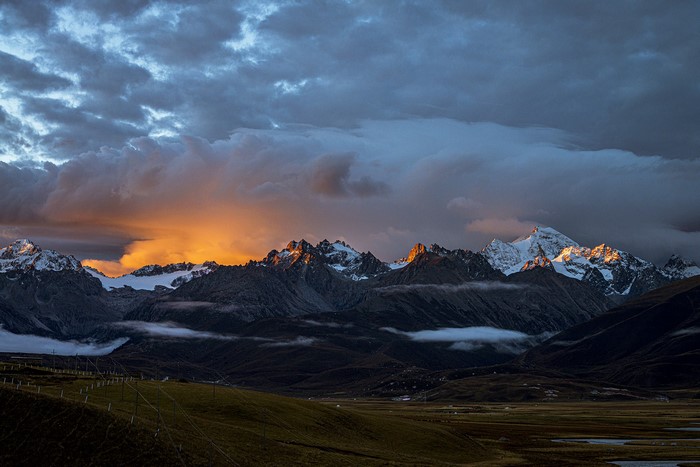 Sunset over snow-capped mountains with dramatic clouds