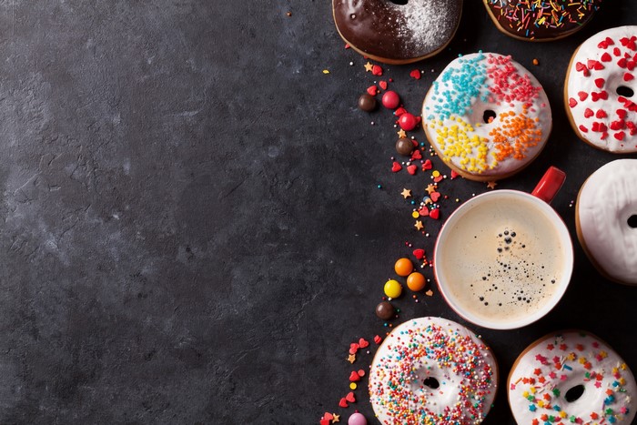 Colorful donuts and coffee on a dark surface
