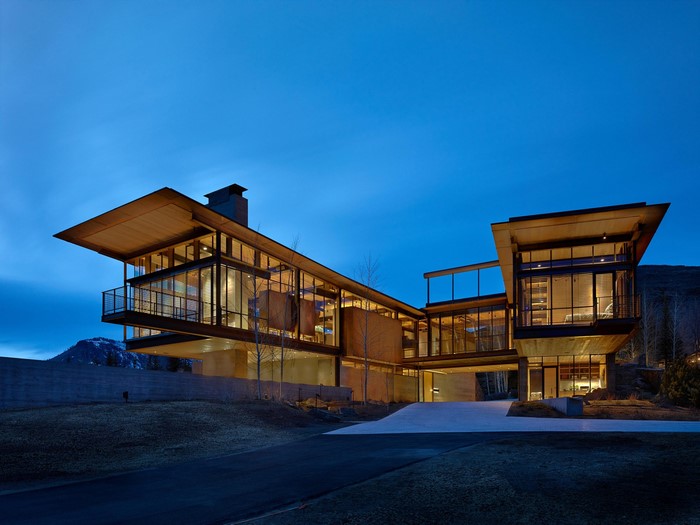 Modern glass mansion with cantilevered sections at dusk