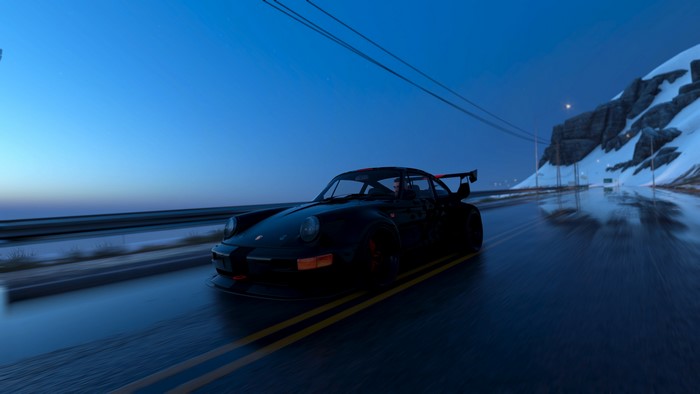 Porsche 911 driving on a wet road at night