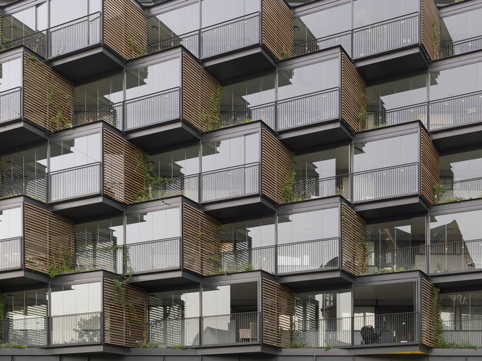 Modern apartment building with glass balconies and wooden louvers