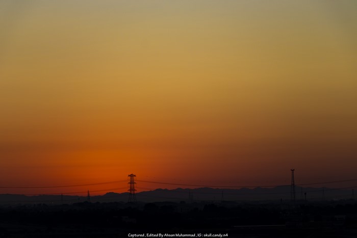 Sunset over mountains with utility poles