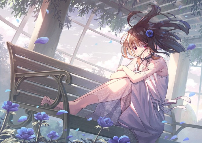 Girl with blue flower in hair sitting on a bench