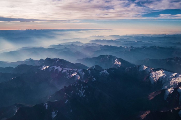 Aerial view of misty mountain ranges with snow-capped peaks