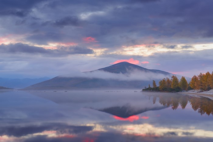 Misty mountain lake reflection at sunset