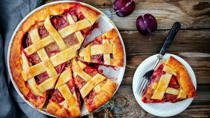 Plum pie with lattice crust on wooden table