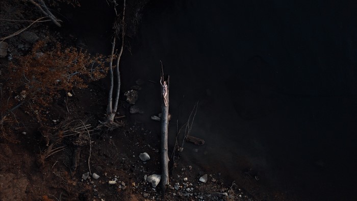 Woman lying on a log by the water