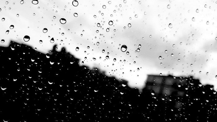 Raindrops on a window with silhouetted buildings