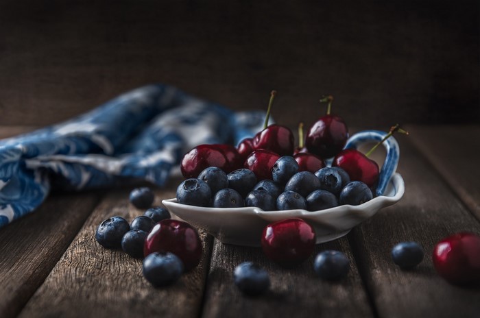 Cherries and blueberries in a bowl on a wooden table